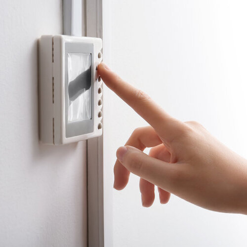 close-up of a woman's hand adjusting a thermostat