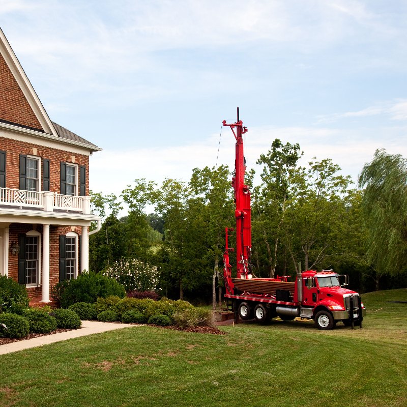 red truck drilling for a geothermal system outside a home