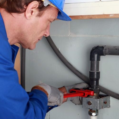 Plumber Tightening a Joint With a Wrench